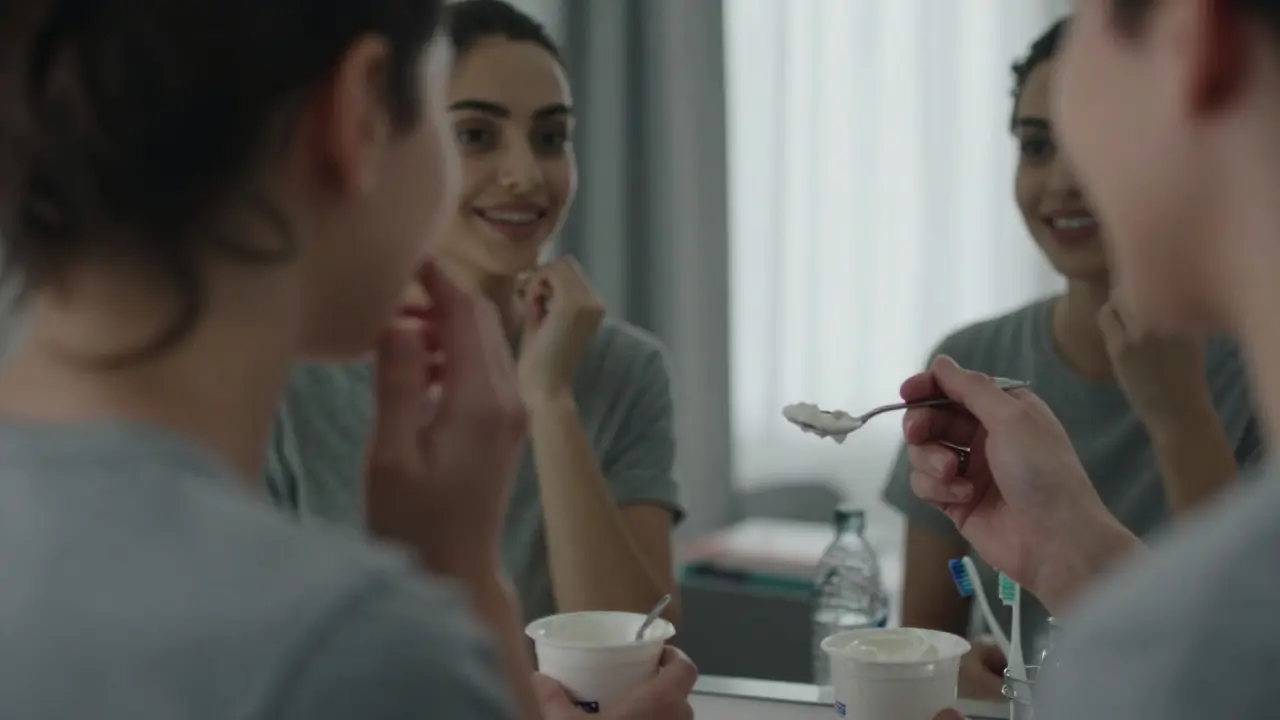 Člověk se dívá do zrcadla, vidí své budoucí úsměv, drží lžíci s měkkým jídlem.